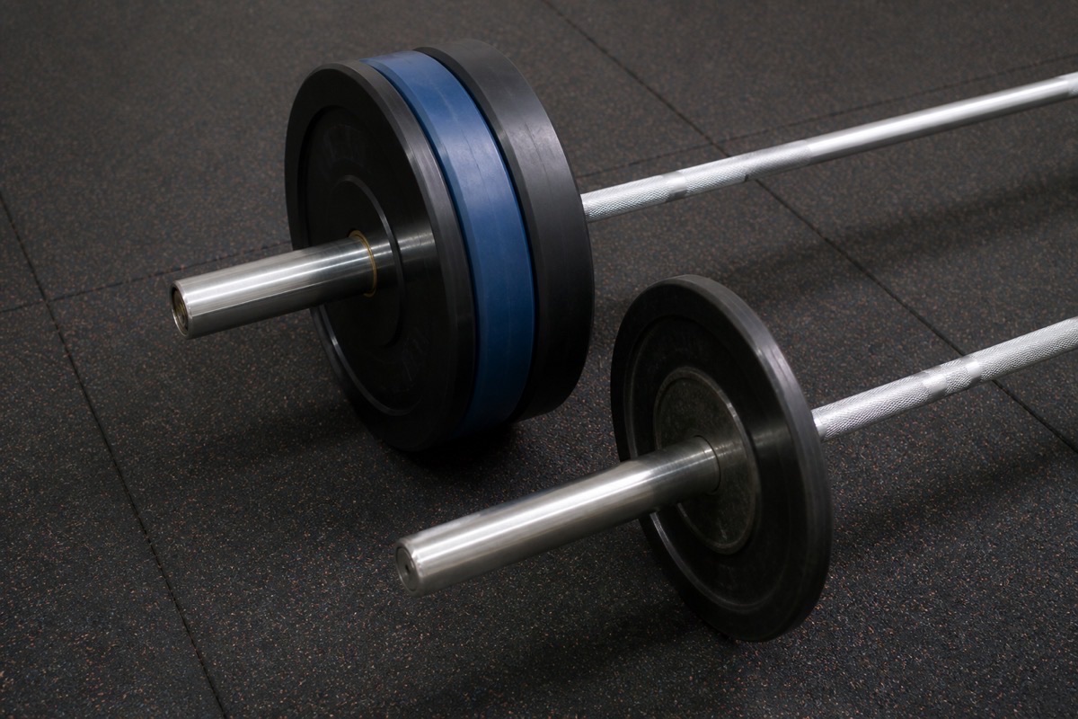 ** Olympic bumper plates on a 50 mm bar beside standard 1-inch plates - **Caption:** Confirm collar diameter before you mix Olympic and standard plate weights in one PO.