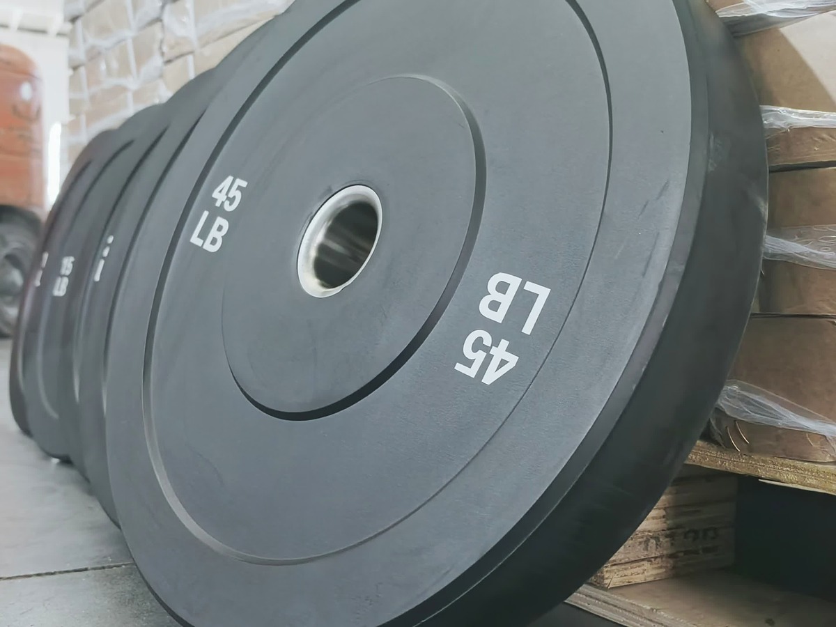 Finished 45 lb rubber weight plate standing beside packed cartons in the factory