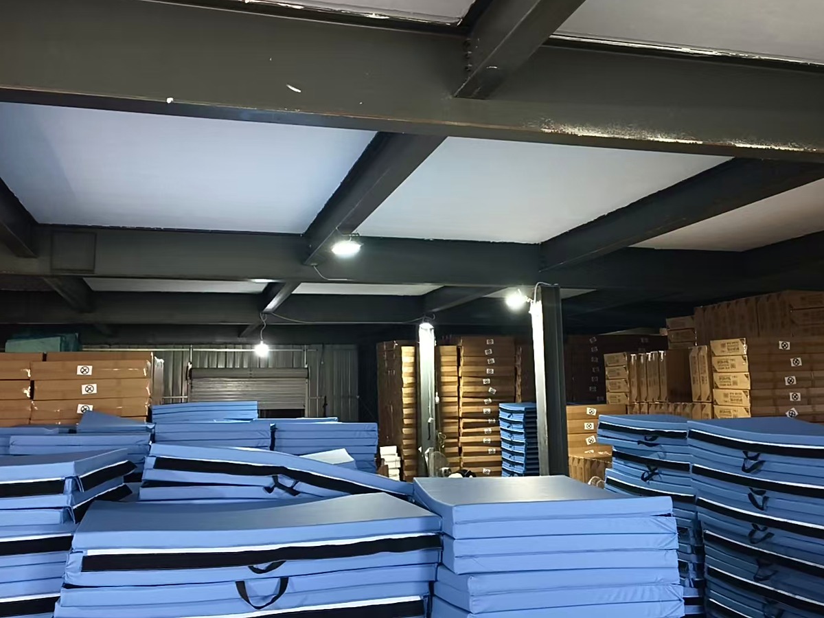 Foldable gym mats stacked in real warehouse stock with cartons in the background